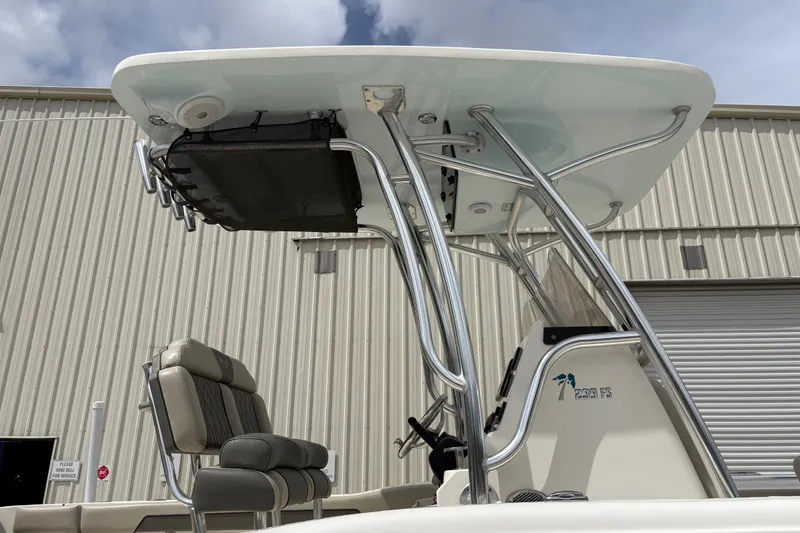 Slide: The Image of 2025 Key West 239 FS boat with T-top and seating, parked near a warehouse. - 10