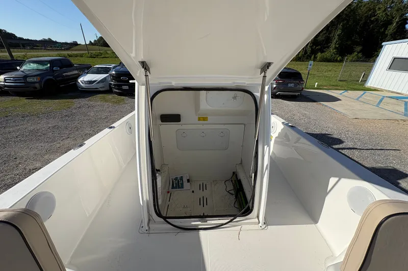 Slide: The Image of 2018 Scout 251 XSS boat interior with open storage compartment, parked cars in background. - 16