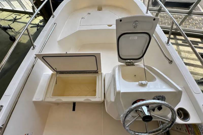 Slide: The Image of 2027 Boston Whaler 160 Super Sport interior with open storage compartments and steering wheel. - 8