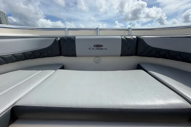 Slide: The Image of 2018 Cobia 301 Center Console boat interior with cushioned seating under a cloudy sky. - 11
