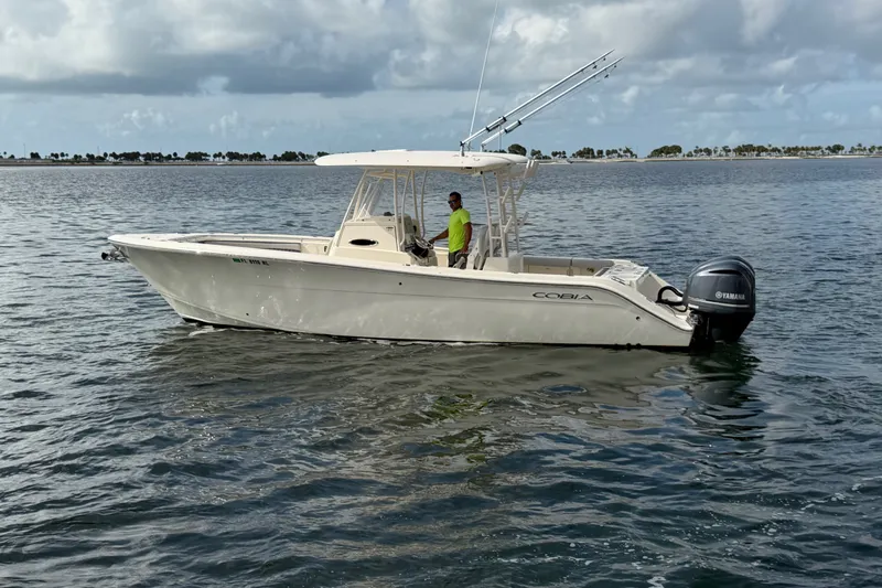 Slide: The Image of 2018 Cobia 301 Center Console boat on calm water with Yamaha engines. - 2