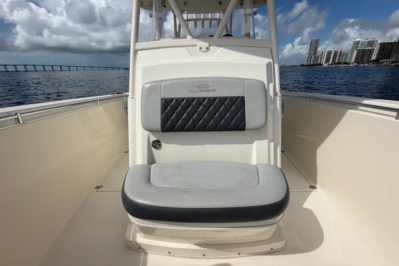 Slide: The Image of 2018 Cobia 301 Center Console boat interior with cushioned seating, ocean view, and city skyline. - 15