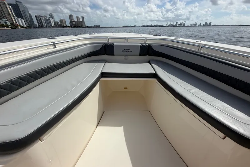 Slide: The Image of 2018 Cobia 301 Center Console boat interior with cushioned seating, overlooking city skyline. - 10