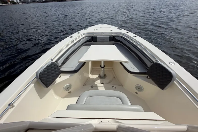 Slide: The Image of 2018 Cobia 301 Center Console boat interior with seating and table on calm water. - 13