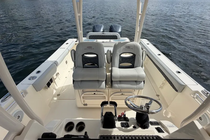 Slide: The Image of 2018 Cobia 301 Center Console boat interior with dual seats and steering wheel on water. - 22