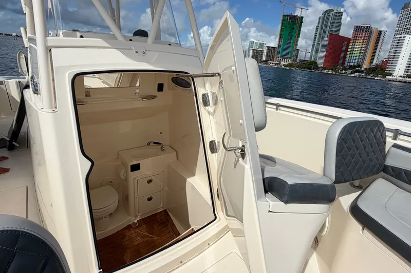 Slide: The Image of 2018 Cobia 301 Center Console boat with open cabin and city skyline background. - 16