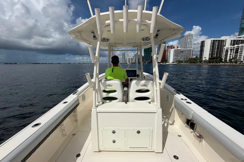 Slide: The Image of 2018 Cobia 301 Center Console boat cruising near city skyline on a sunny day. - 38