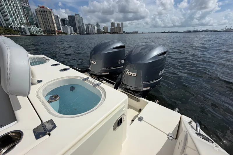 Slide: The Image of 2018 Cobia 301 Center Console boat with twin Yamaha engines on a city waterfront. - 37