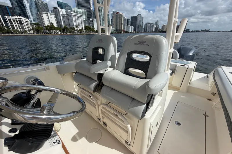 Slide: The Image of 2018 Cobia 301 Center Console boat interior with city skyline backdrop. - 23