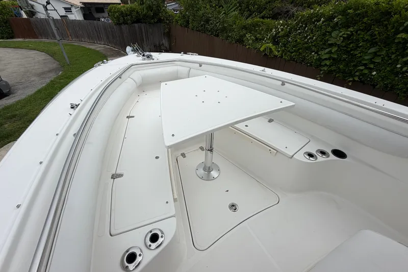 Slide: The Image of 2006 Boston Whaler 270 Outrage boat deck with table, surrounded by lush greenery. - 37