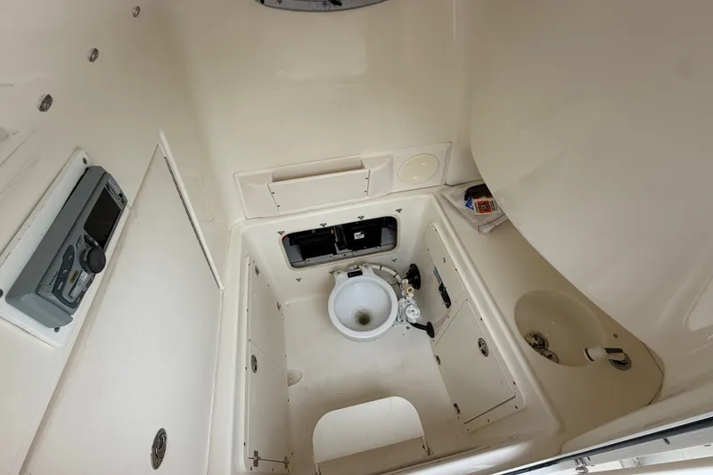 Slide: The Image of Interior of 2006 Boston Whaler 270 Outrage boat, featuring a compact marine toilet setup. - 31
