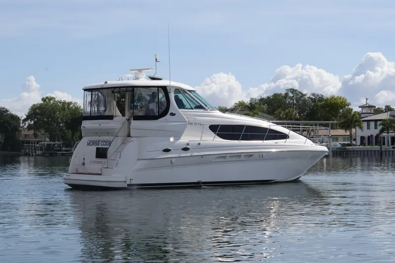 Slide: The Image of 2006 Sea Ray 40 Motor Yacht on calm water, surrounded by trees and houses. - 2