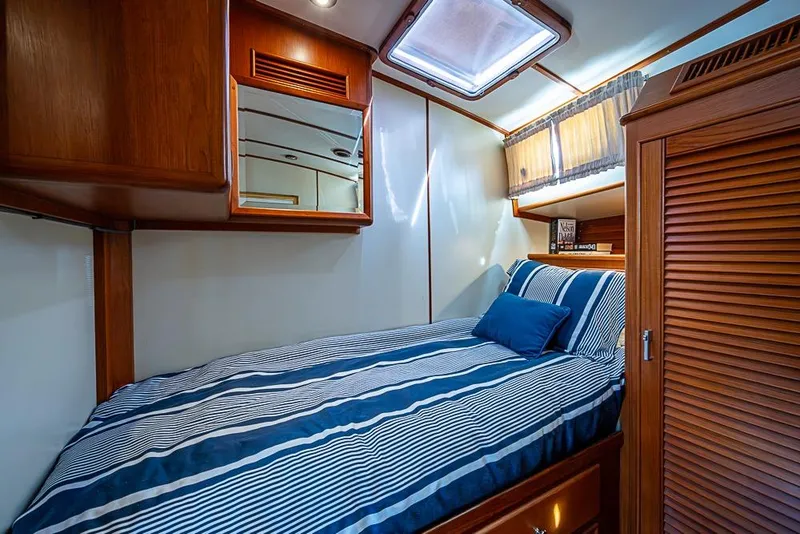 Slide: The Image of Cozy cabin interior of 2001 Grand Banks 49 Eastbay HX with striped bedding and wooden accents. - 49