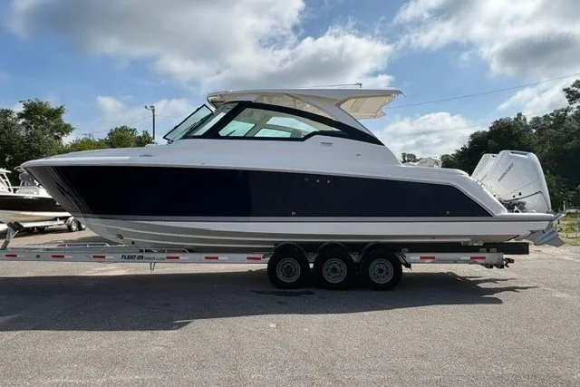The Image of 2027 Tiara Yachts 34 LX on trailer, sleek design, parked outdoors under cloudy sky. - 0