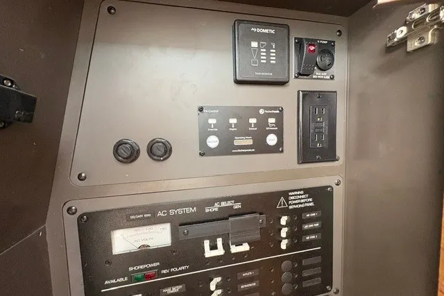 Slide: The Image of Electrical control panel of 2027 Tiara Yachts 34 LX, featuring AC system and power switches. - 17