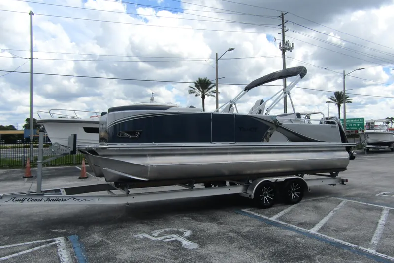 Slide: The Image of 2026 Tahoe Pontoon LTZ Versatile Rear Bench Wind Shield 23 on trailer, parked outdoors. - 6