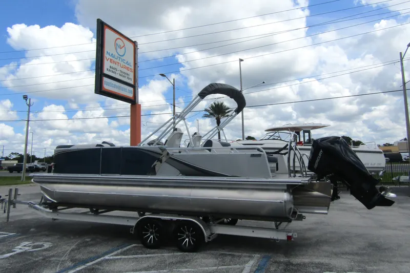 Slide: The Image of 2026 Tahoe Pontoon LTZ Versatile Rear Bench Wind Shield 23 on trailer at dealership. - 1
