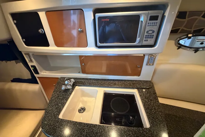 Slide: The Image of 2008 Chaparral Signature 270 boat kitchen with microwave, sink, and stove. - 36