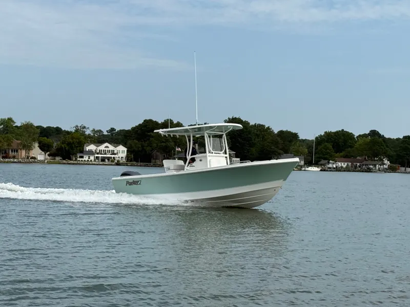 Slide: The Image of A 2026 Parker 230 Coastal Elite boat cruising on calm waters with a wooded shoreline. - 1