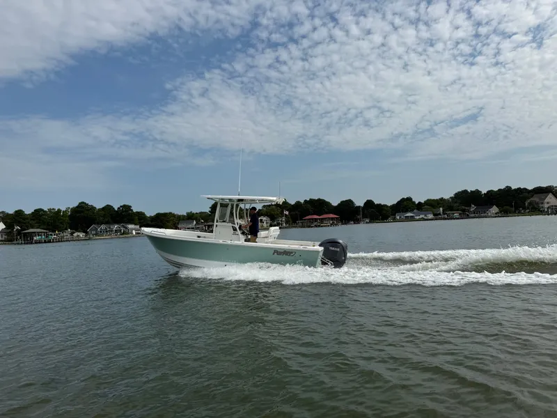 Slide: The Image of A Parker 230 Coastal Elite boat speeds across the water, surrounded by a calm coastal landscape. - 6
