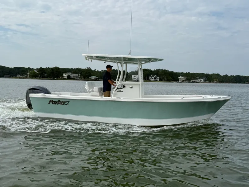 Slide: The Image of Parker 230 Coastal Elite 2026 on calm water with a driver, surrounded by trees and houses. - 4