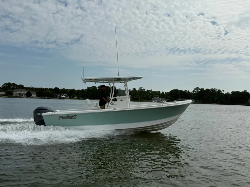 Slide: The Image of Parker 230 Coastal Elite 2026 on the water with an outboard motor, under a cloudy sky. - 2