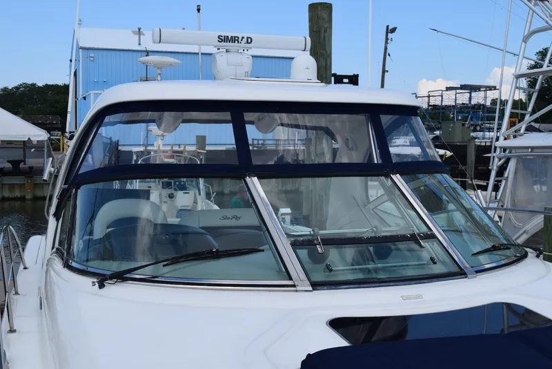 Slide: The Image of 2004 Sea Ray 390 Sundancer yacht docked at marina, featuring sleek windshield design. - 10