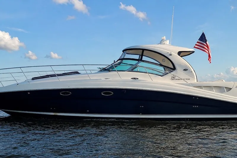 The Image of 2004 Sea Ray 390 Sundancer yacht on water, American flag, blue sky background. - 0