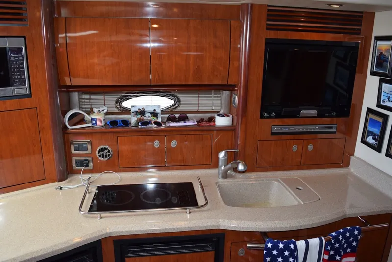Slide: The Image of 2004 Sea Ray 390 Sundancer interior with kitchenette, TV, and wooden cabinetry. - 24