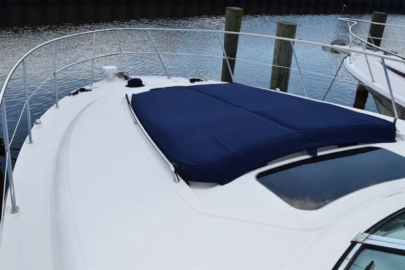 Slide: The Image of 2004 Sea Ray 390 Sundancer yacht with blue sunpad on deck, docked by water. - 7