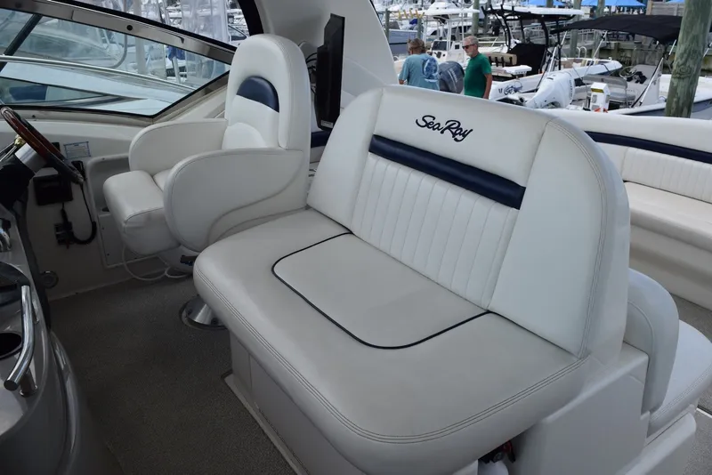 Slide: The Image of 2004 Sea Ray 390 Sundancer cockpit with white seating and helm, docked at marina. - 16