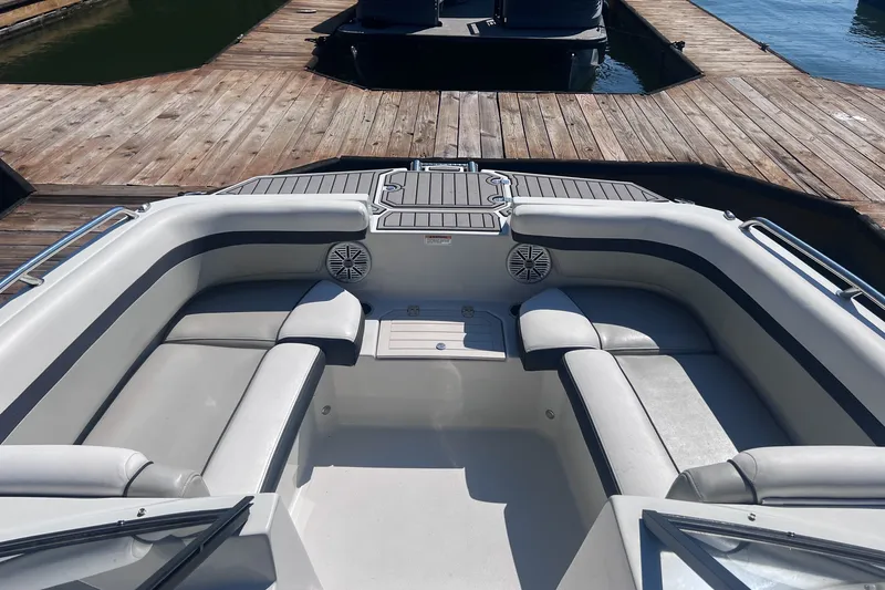Slide: The Image of 2023 Starcraft SVX 210 IO boat interior with cushioned seating and speakers at a dock. - 3