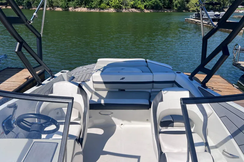 Slide: The Image of 2023 Starcraft SVX 210 IO boat interior with seating, docked on a calm lake. - 6