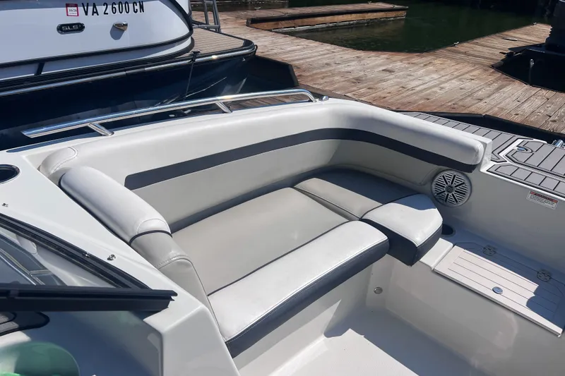 Slide: The Image of 2023 Starcraft SVX 210 IO boat interior with cushioned seating and speaker, docked by wooden pier. - 4