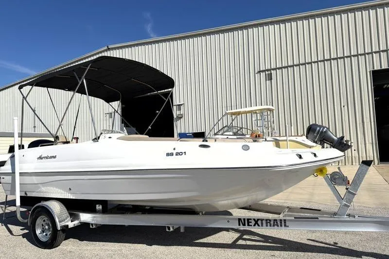 The Image of 2022 Hurricane SunDeck Sport 201 OB boat on trailer, parked outside a warehouse. - 1