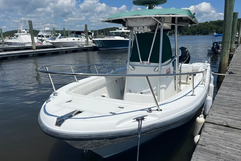 The Image of 1999 Boston Whaler 230 Outrage docked at marina under clear skies. - 0