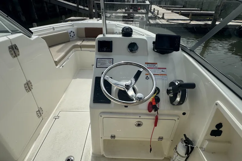 Slide: The Image of 2024 Cobia 220 Dual Console boat interior with steering wheel and control panel. - 5