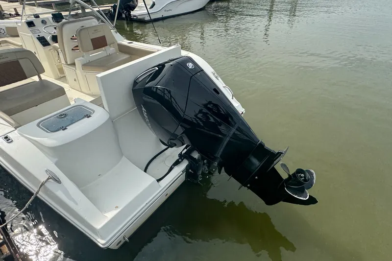 Slide: The Image of 2024 Cobia 220 Dual Console boat with powerful outboard motor, docked on calm water. - 8