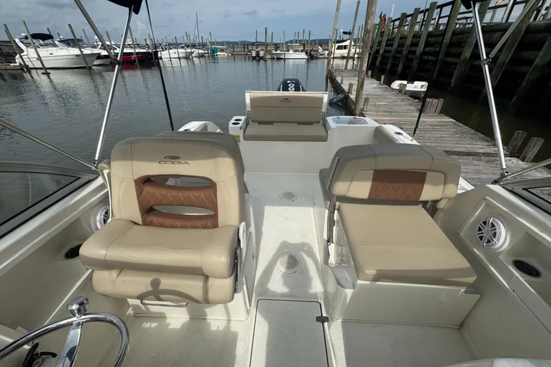 Slide: The Image of 2024 Cobia 220 Dual Console boat interior at marina, featuring comfortable seating and sleek design. - 6