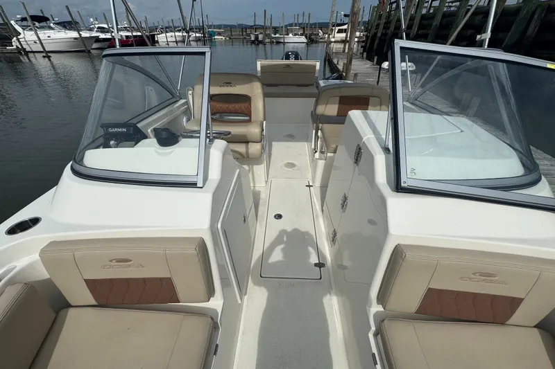 Slide: The Image of 2024 Cobia 220 Dual Console boat interior at marina, featuring seating and windshield. - 3