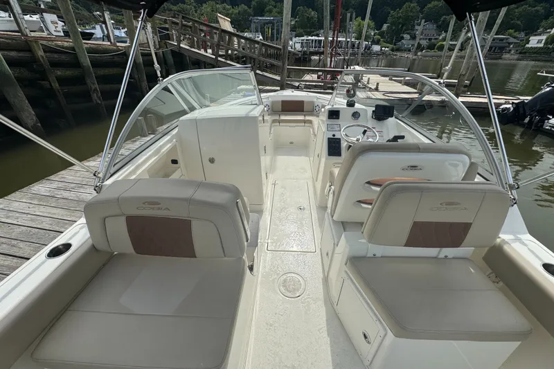 Slide: The Image of 2024 Cobia 220 Dual Console boat interior at dock, featuring seating and helm controls. - 4