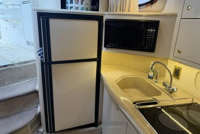 Slide: The Image of Kitchen area of a 1997 Sea Ray Sundancer 400 yacht with fridge, microwave, and sink. - 29