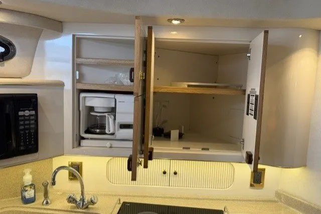 Slide: The Image of 1997 Sea Ray Sundancer 400 yacht kitchen with open cabinets, coffee maker, and sink. - 20