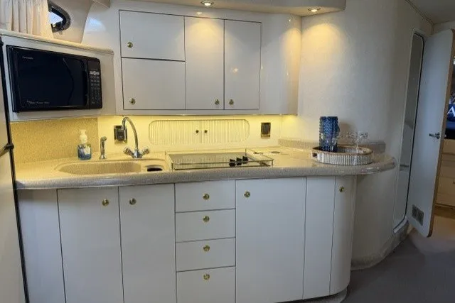 Slide: The Image of 1997 Sea Ray Sundancer 400 yacht kitchen with white cabinets and modern appliances. - 30