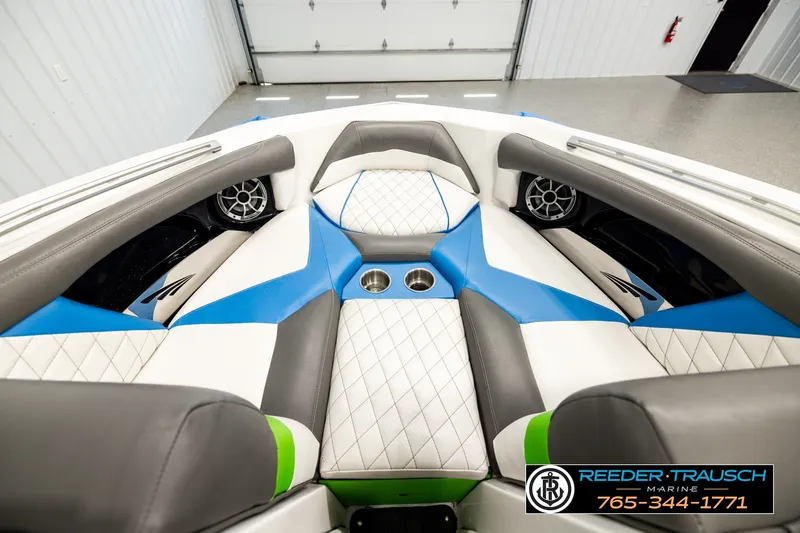Slide: The Image of 2013 Tigé RZR boat interior with blue and white seating, cup holders, and speakers. - 14