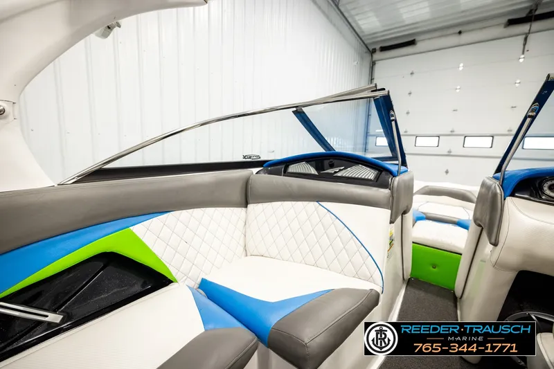 Slide: The Image of 2013 Tigé RZR boat interior with blue, green, and white seating in a garage setting. - 27