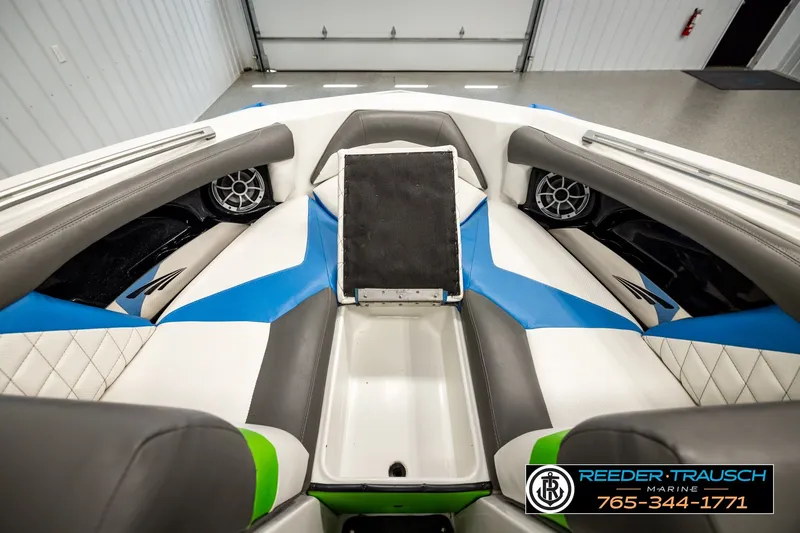 Slide: The Image of 2013 Tigé RZR boat interior with blue and white seating, speakers, and storage compartment. - 26