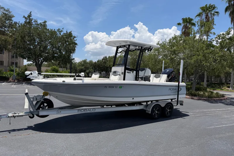The Image of 2023 Robalo 226 Cayman boat on trailer in sunny parking lot. - 1
