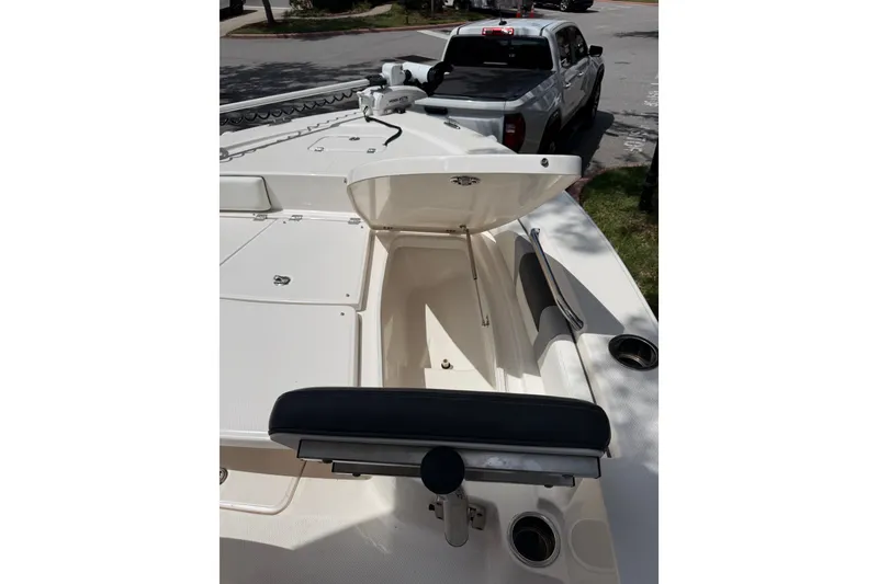 Slide: The Image of 2023 Robalo 226 Cayman boat with open storage compartment, parked near a white truck. - 9