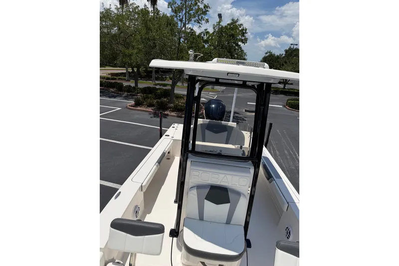 Slide: The Image of 2023 Robalo 226 Cayman boat interior with seating and console, parked outdoors. - 15